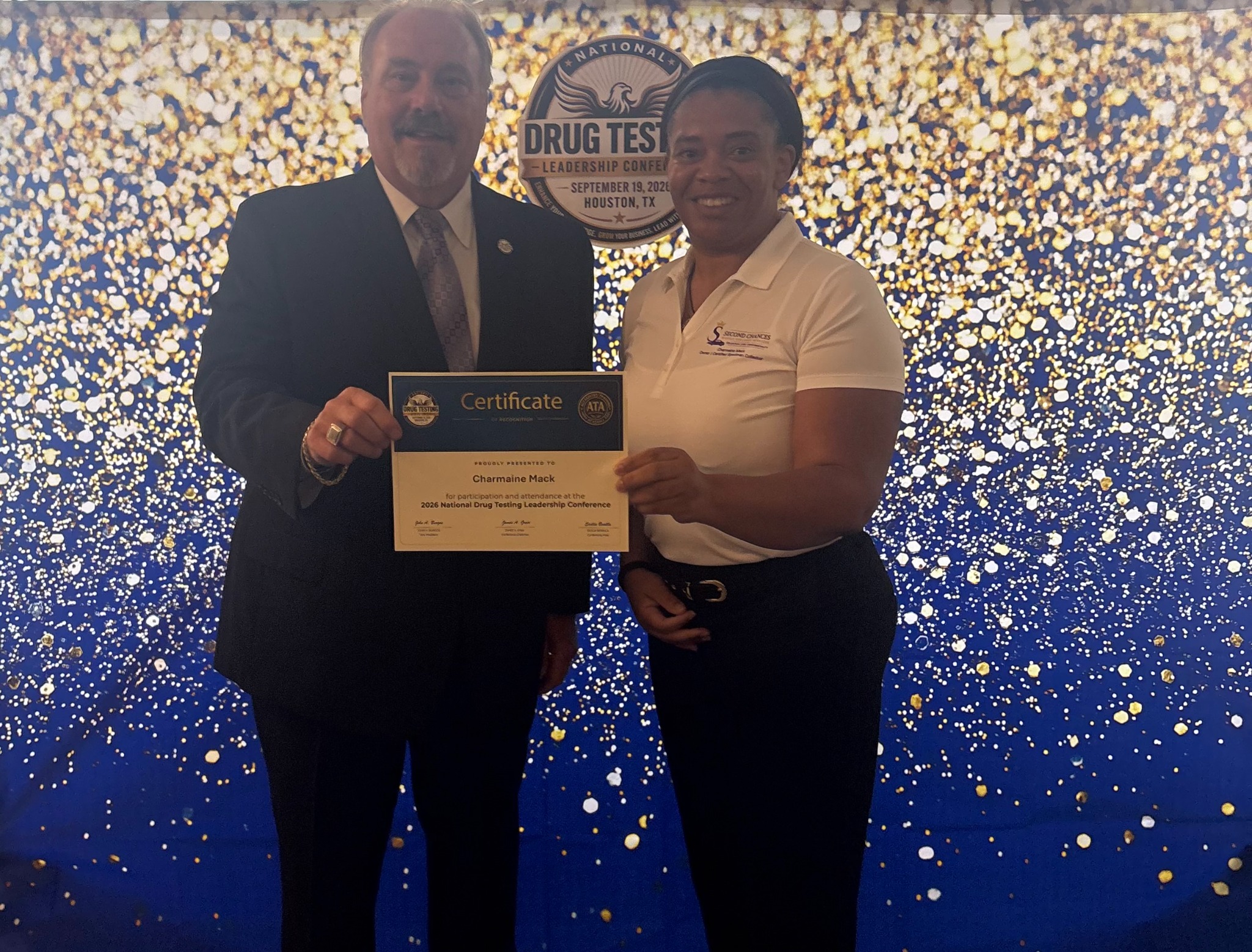 Charmaine Mack posing with a conference representative while holding her attendance certificate